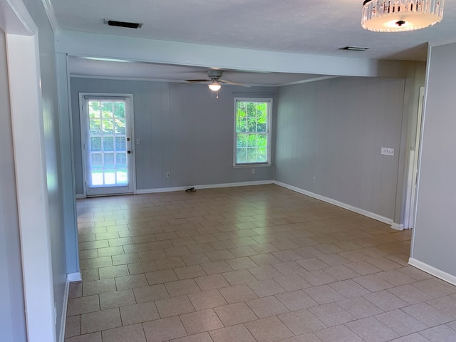 empty room featuring ceiling fan, light tile patterned floors, and ornamental molding