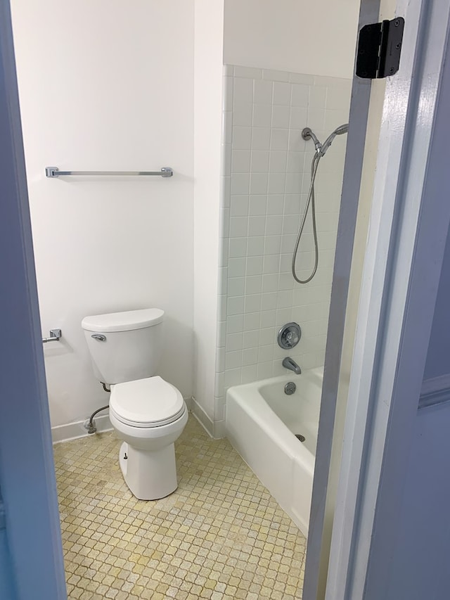 bathroom with tile patterned flooring, tiled shower / bath combo, and toilet