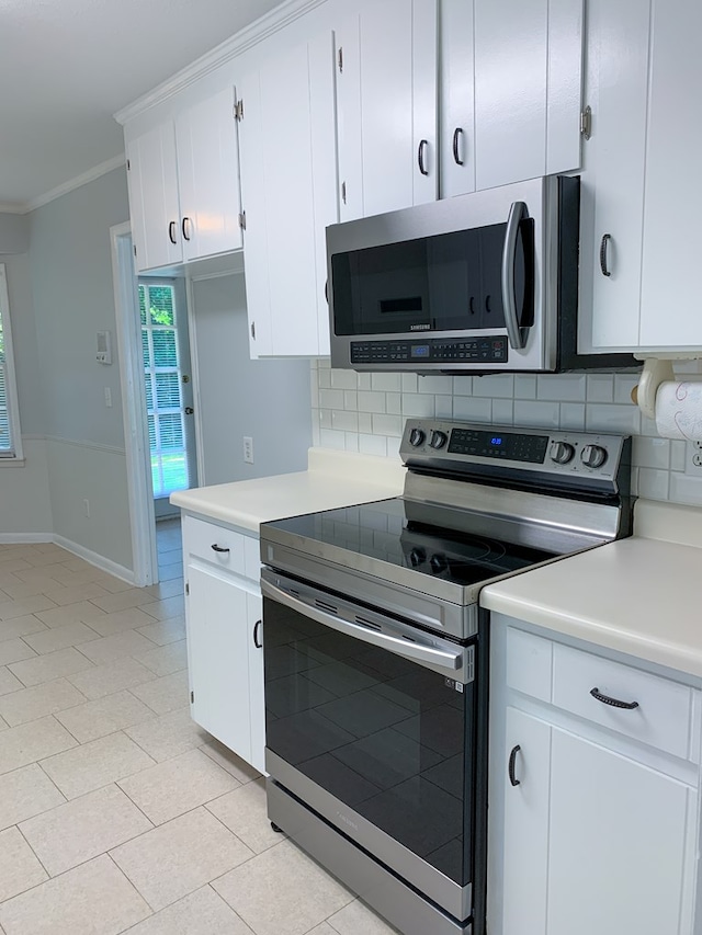 kitchen with white cabinets, appliances with stainless steel finishes, backsplash, and crown molding