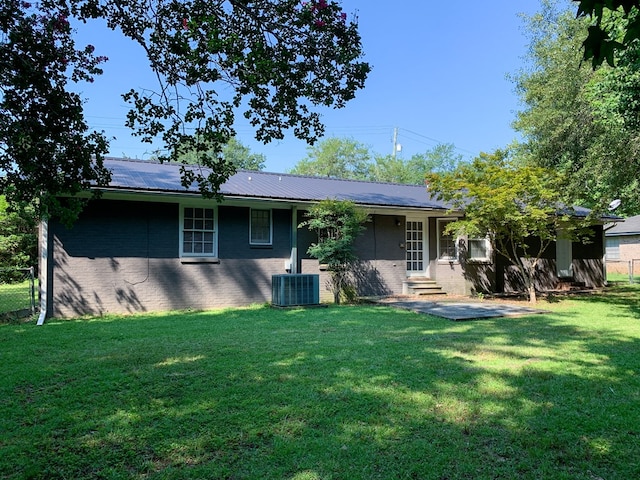 rear view of property featuring a lawn and central AC unit