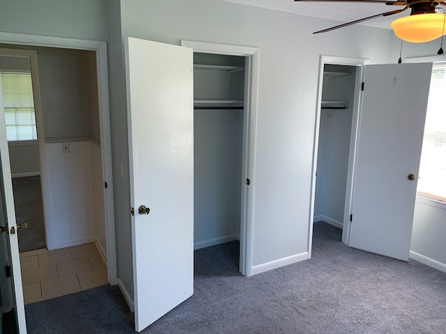 unfurnished bedroom featuring carpet, ceiling fan, and multiple closets