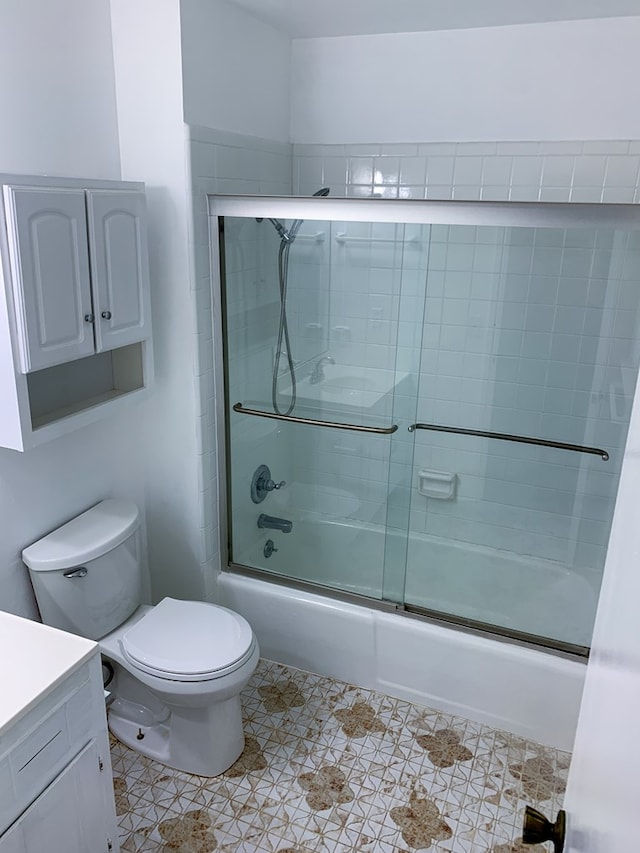 full bathroom featuring shower / bath combination with glass door, tile patterned flooring, vanity, and toilet