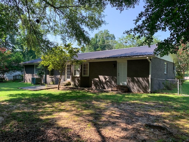 rear view of property with cooling unit and a yard