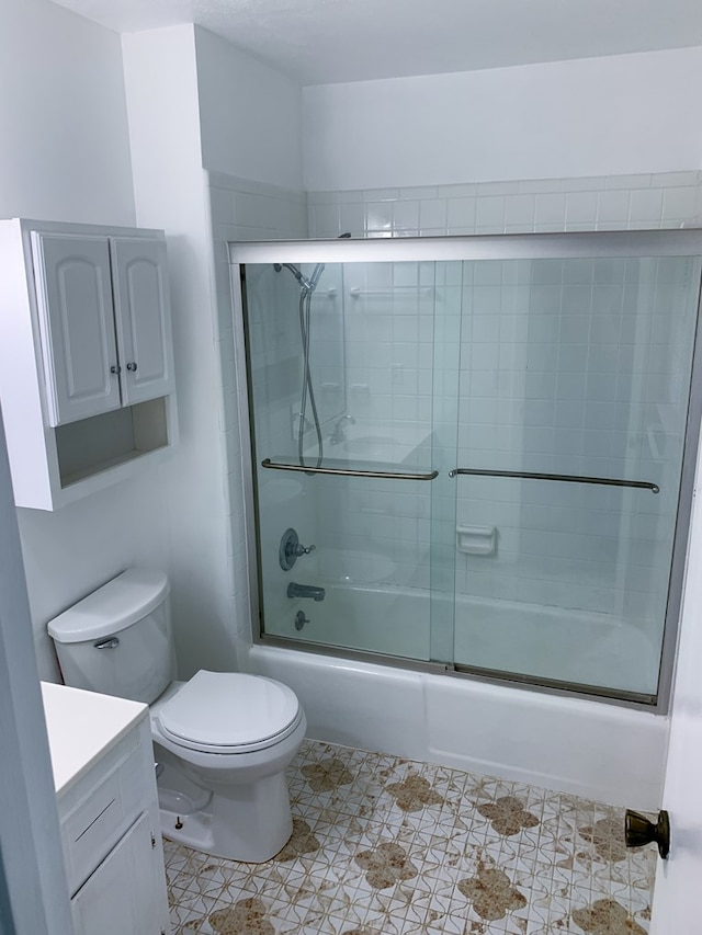 full bathroom featuring shower / bath combination with glass door, tile patterned floors, vanity, and toilet