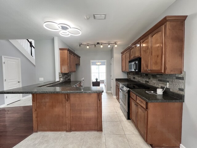 305 Millenia St, Enterprise, AL 36330 - kitchen featuring stainless steel electric range oven, black microwave, a peninsula, decorative backsplash, and a breakfast bar area