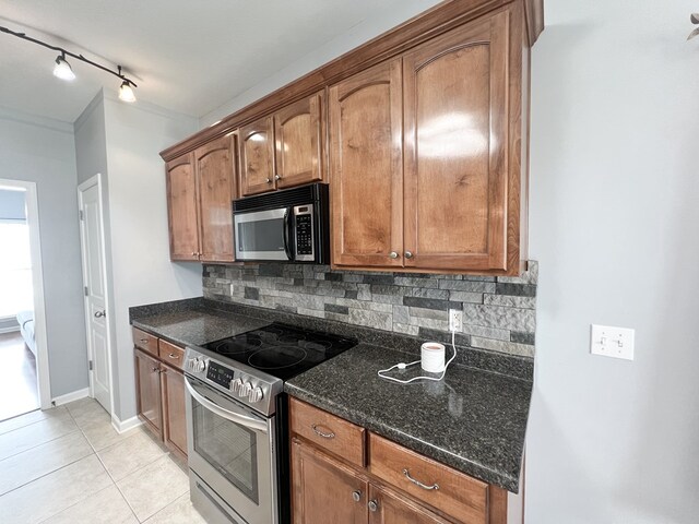 305 Millenia St, Enterprise, AL 36330 - kitchen featuring appliances with stainless steel finishes, decorative backsplash, light tile patterned floors, dark stone countertops, and brown cabinets