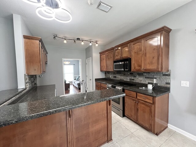 305 Millenia St, Enterprise, AL 36330 - kitchen with appliances with stainless steel finishes, backsplash, a peninsula, light tile patterned floors, and dark stone counters