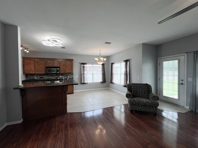 305 Millenia St, Enterprise, AL 36330 - kitchen featuring stainless steel microwave, dark countertops, a chandelier, light wood-style floors, and backsplash