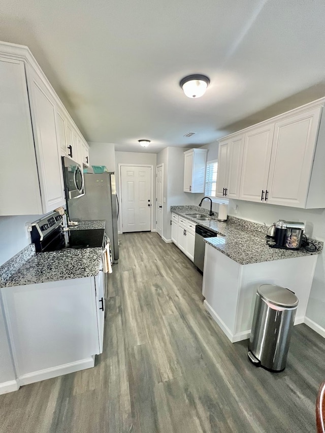 kitchen with light wood-type flooring, a sink, white cabinetry, appliances with stainless steel finishes, and baseboards