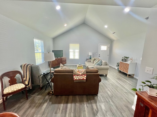 living area with vaulted ceiling, wood finished floors, baseboards, and visible vents