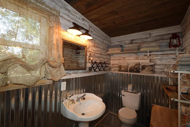 bathroom with toilet, wood ceiling, wooden walls, and sink