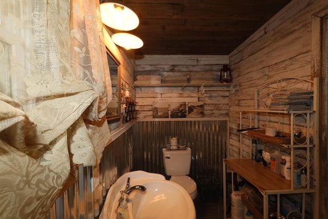 bathroom with wood walls, toilet, wood ceiling, and sink