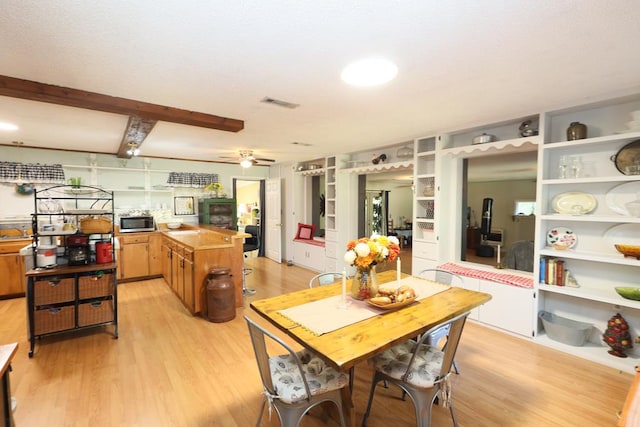 dining area with ceiling fan, light hardwood / wood-style floors, and beam ceiling