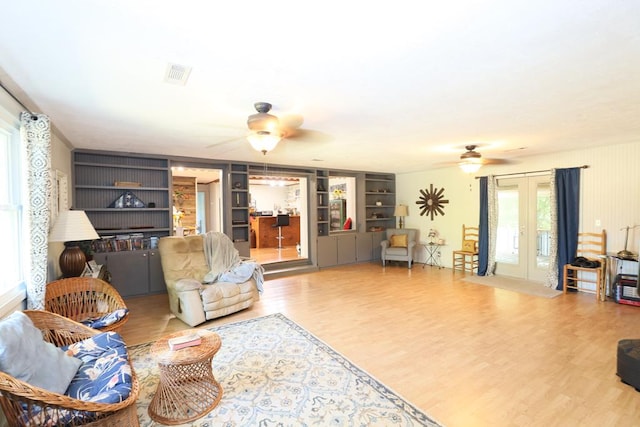 living room featuring french doors, built in features, and wood-type flooring