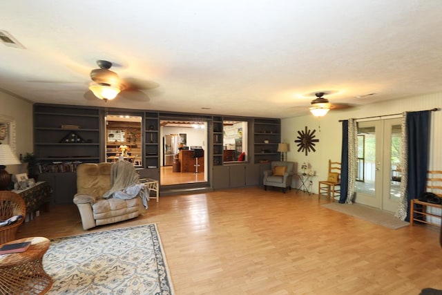 living room featuring built in shelves, french doors, ceiling fan, and hardwood / wood-style floors