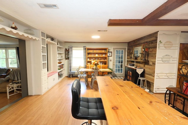 dining space with hardwood / wood-style flooring, wood walls, and beamed ceiling