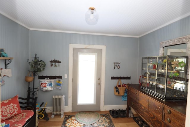 foyer with radiator heating unit, ornamental molding, and wood-type flooring