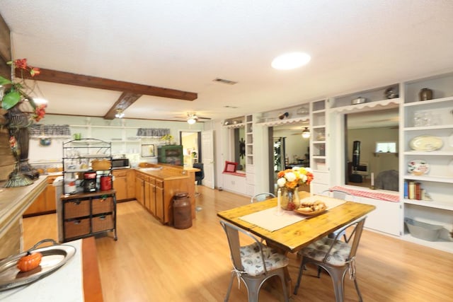 dining area featuring beamed ceiling, built in shelves, and light wood-type flooring