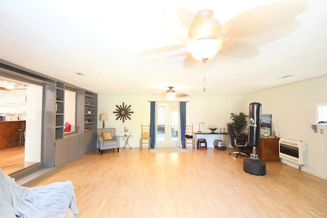 interior space featuring hardwood / wood-style floors, french doors, built in shelves, ceiling fan, and heating unit