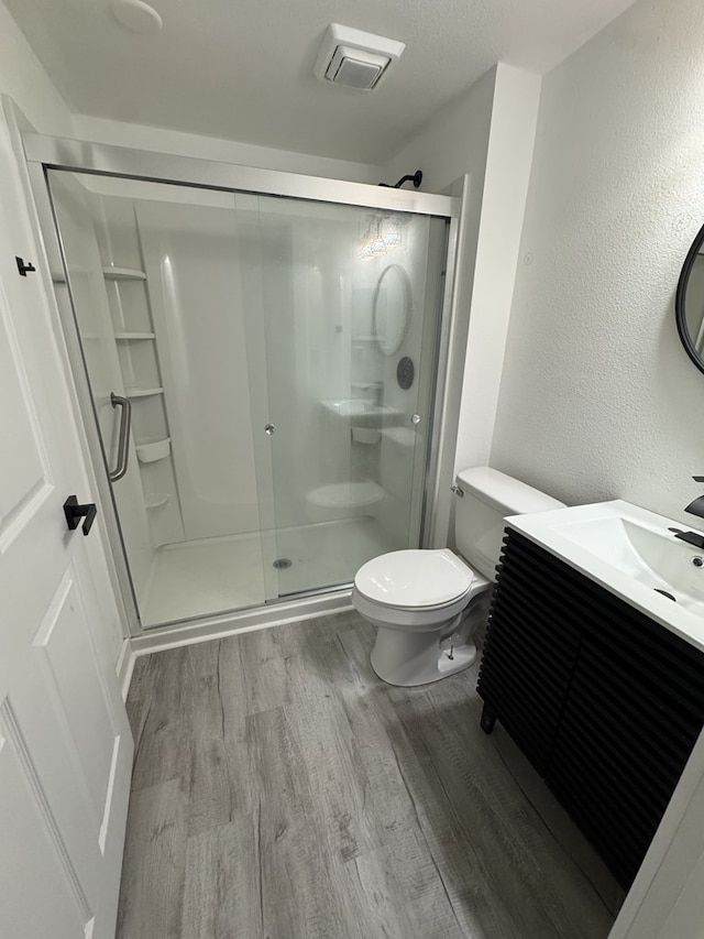 full bathroom featuring visible vents, wood finished floors, toilet, and a shower stall
