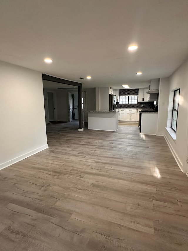 unfurnished living room featuring recessed lighting, baseboards, and light wood-style floors