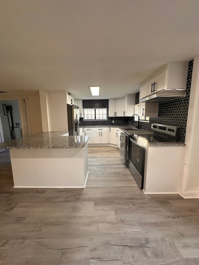 kitchen with a sink, appliances with stainless steel finishes, dark stone countertops, and white cabinetry