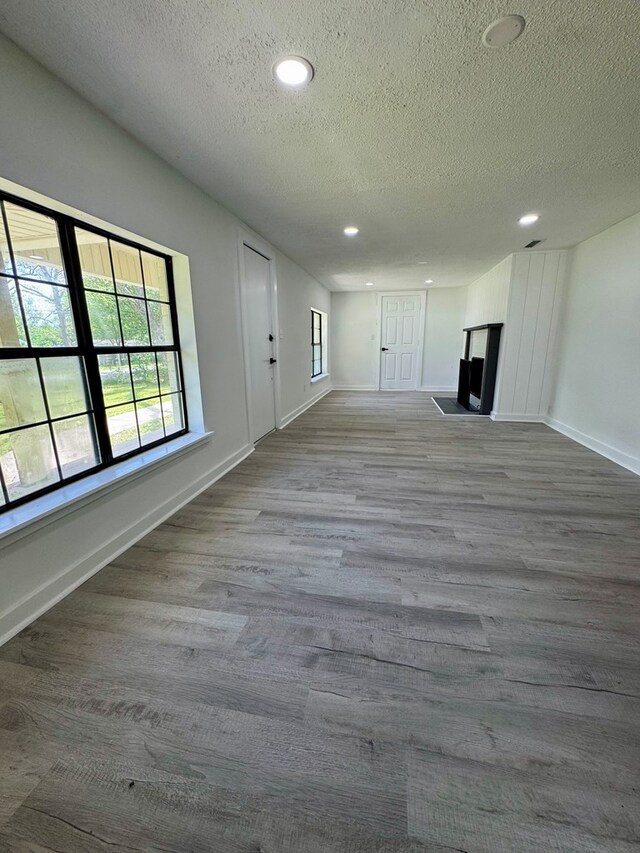 unfurnished living room featuring baseboards, a textured ceiling, and wood finished floors