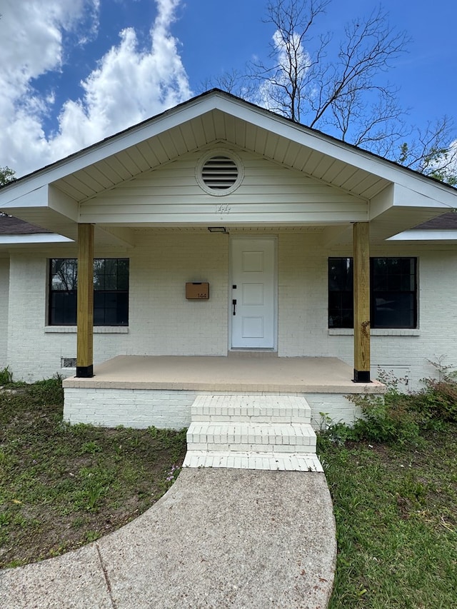 view of exterior entry with covered porch and brick siding
