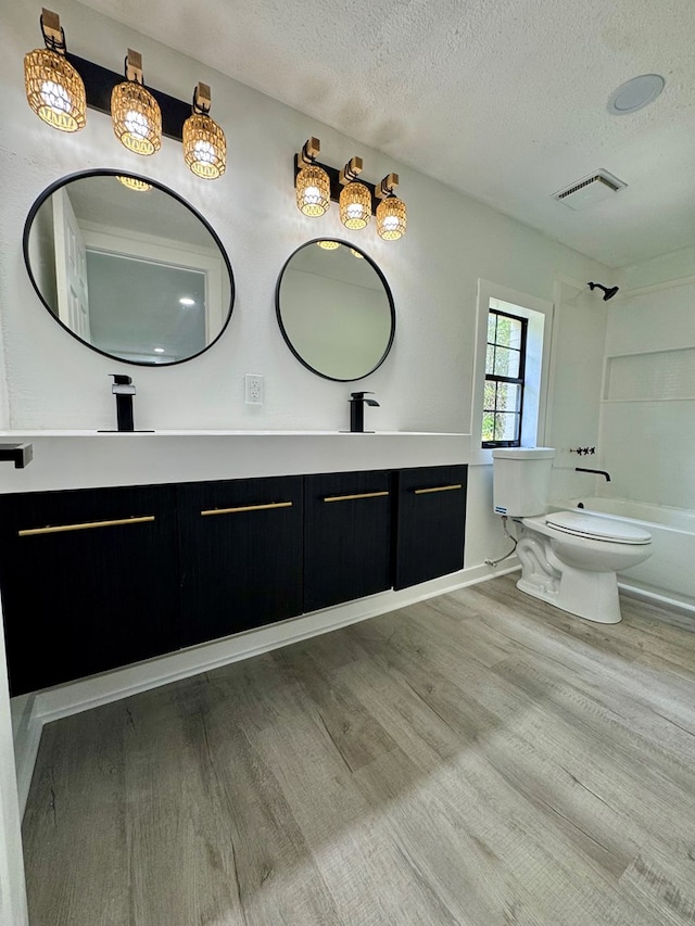 full bathroom featuring double vanity, a textured ceiling, visible vents, wood finished floors, and toilet