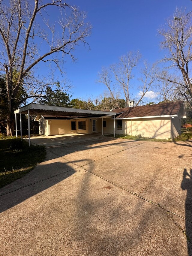 view of front of house featuring a carport, a chimney, and concrete driveway