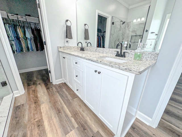 full bath featuring a spacious closet, a tile shower, a sink, and wood finished floors