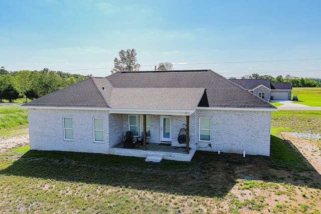 back of house with a patio, brick siding, and a lawn