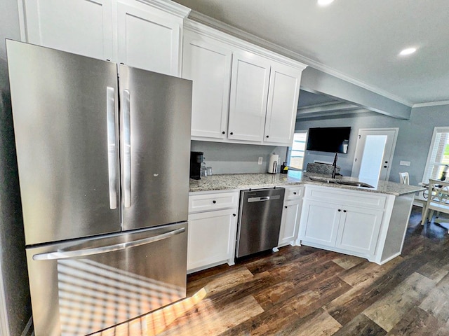 kitchen featuring dark wood-style flooring, a peninsula, crown molding, appliances with stainless steel finishes, and a sink