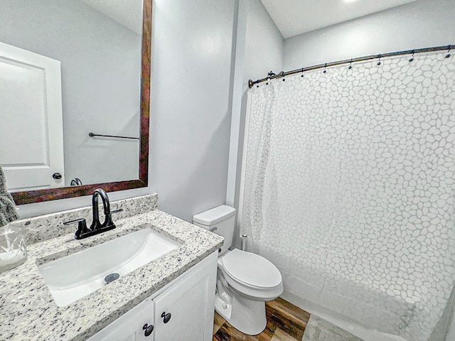 bathroom with toilet, curtained shower, wood finished floors, and vanity