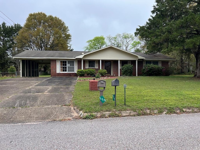 ranch-style house featuring driveway, brick siding, a front yard, and a carport