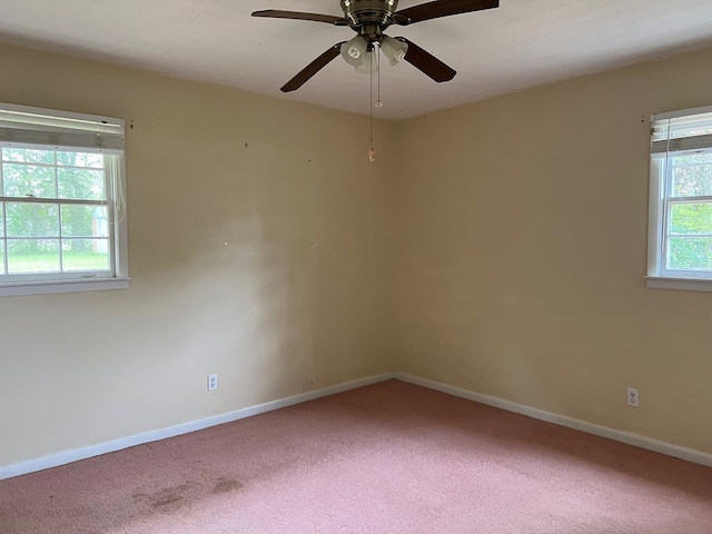 unfurnished room with baseboards, a wealth of natural light, a ceiling fan, and carpet