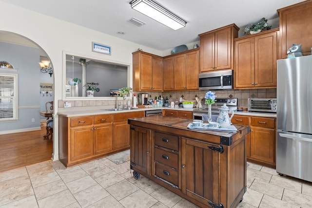 114 Bluffton Rd, Dothan, AL 36301 - kitchen with stainless steel appliances, decorative backsplash, and brown cabinetry