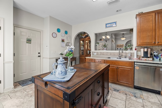114 Bluffton Rd, Dothan, AL 36301 - kitchen featuring dishwasher, brown cabinetry, arched walkways, tasteful backsplash, and a kitchen island