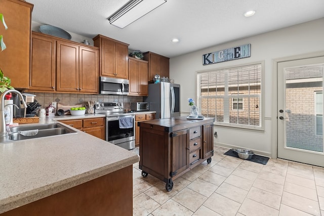 114 Bluffton Rd, Dothan, AL 36301 - kitchen featuring stainless steel appliances, tasteful backsplash, light tile patterned floors, brown cabinets, and light countertops