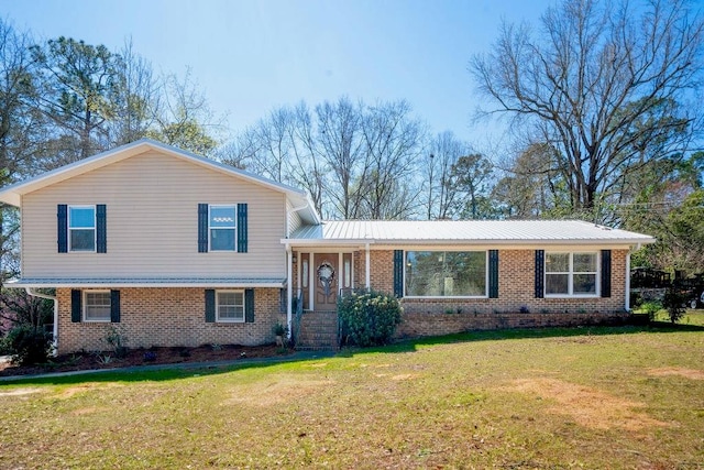 tri-level home featuring brick siding, a front lawn, and metal roof