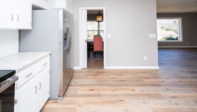 kitchen with light wood finished floors, baseboards, and white cabinetry