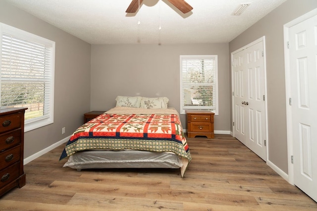 bedroom with visible vents, baseboards, ceiling fan, and wood finished floors