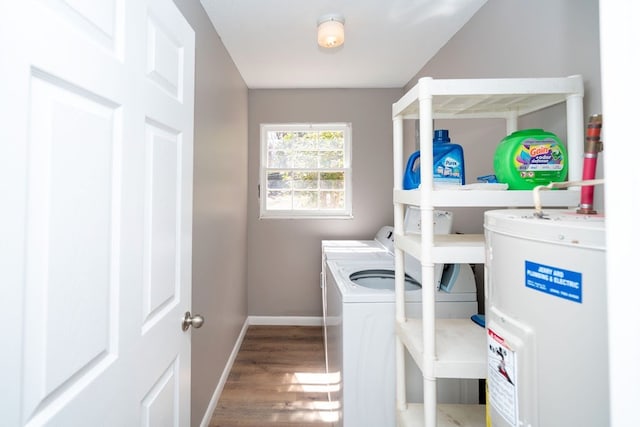 clothes washing area with water heater, baseboards, washer and clothes dryer, laundry area, and wood finished floors