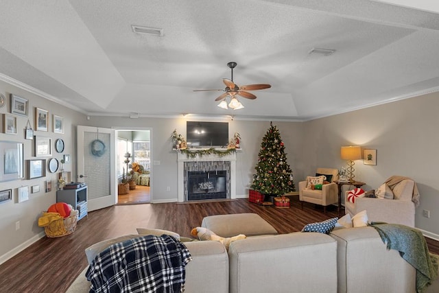 living room with wood-type flooring, a tray ceiling, ceiling fan, and a tiled fireplace