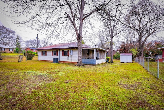 back of property with an outdoor structure, metal roof, a yard, and fence