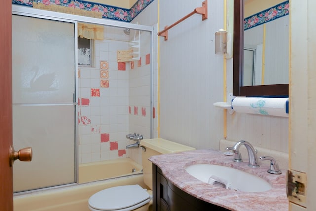 bathroom with wallpapered walls, toilet, vanity, and bath / shower combo with glass door