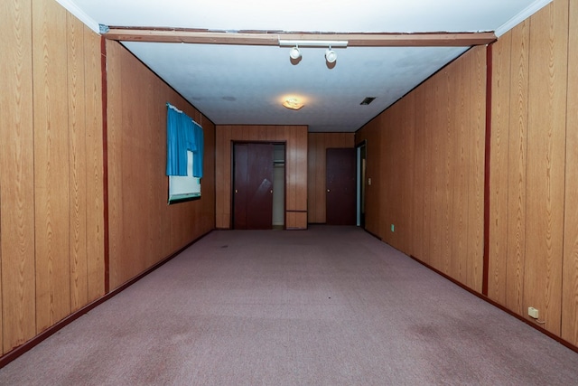 unfurnished room featuring light carpet, wooden walls, and visible vents