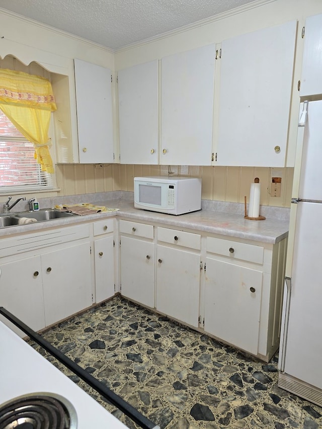 kitchen with a textured ceiling, sink, white cabinets, and white appliances