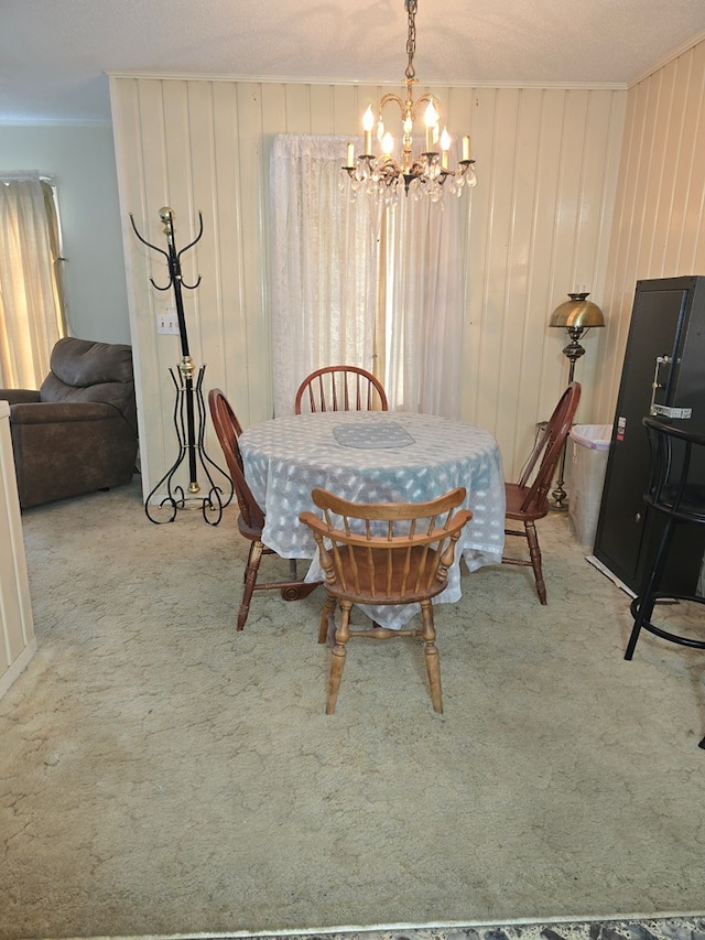 dining room featuring light carpet, ornamental molding, a textured ceiling, wooden walls, and an inviting chandelier