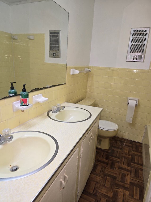 bathroom with vanity, toilet, parquet flooring, and tile walls